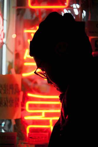 light silhouette of man near yellow and red LED sign chinatown